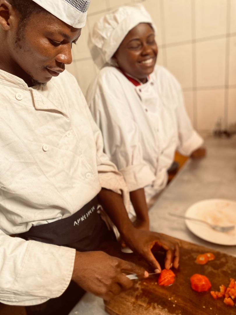 chef homme et apprenants femme entrain de couper des tomates